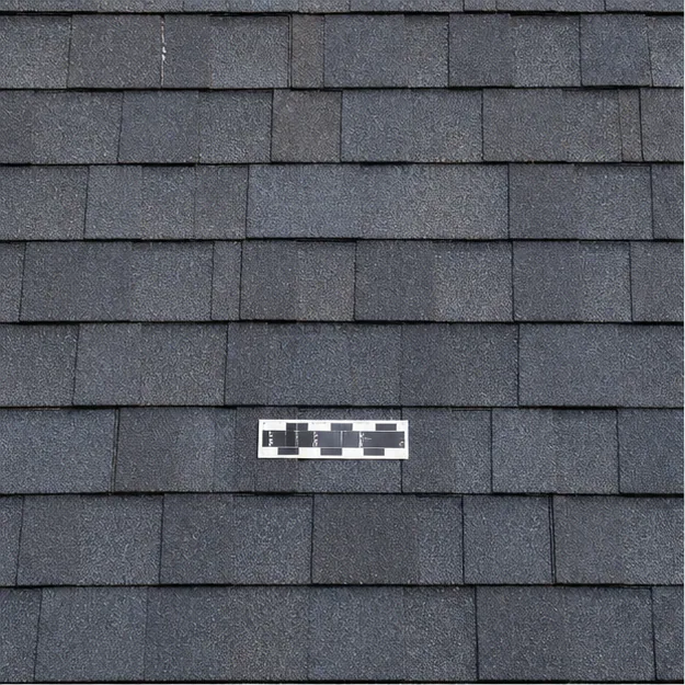 Completed localized asphalt shingle repair with measurement marker